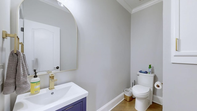 bathroom with wood finished floors, toilet, vanity, baseboards, and crown molding