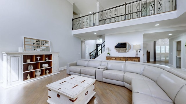 living area with recessed lighting, wood finished floors, baseboards, stairway, and a towering ceiling