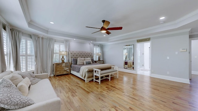 bedroom featuring ornamental molding, multiple windows, light wood-style flooring, and a tray ceiling