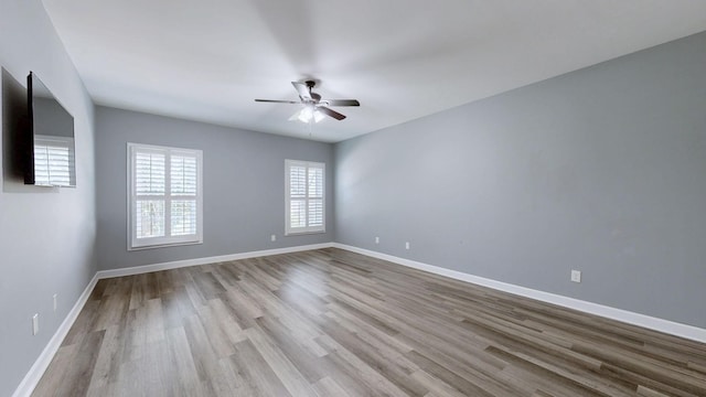 empty room featuring wood finished floors, a ceiling fan, and baseboards