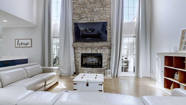 living room with wood finished floors, a fireplace, and a towering ceiling