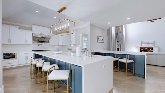 kitchen featuring ornamental molding, recessed lighting, a kitchen breakfast bar, and under cabinet range hood