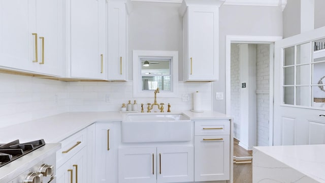 kitchen with white cabinetry, range, a sink, light wood-type flooring, and backsplash