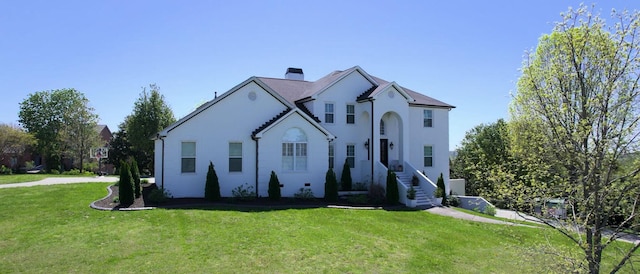 french country style house with a front lawn and stucco siding