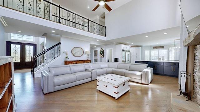 living area with light wood-style floors, ceiling fan, stairs, and a high ceiling