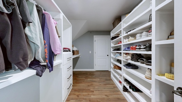 walk in closet with vaulted ceiling and light wood-style flooring