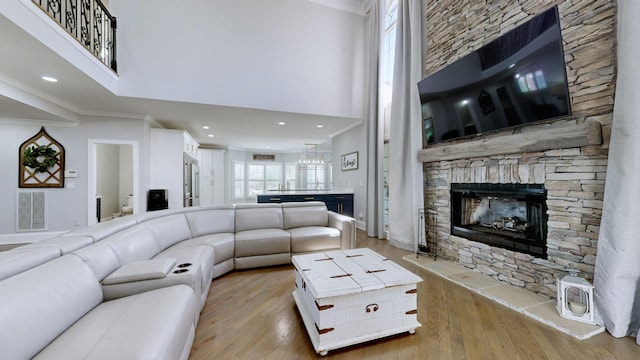 living area with crown molding, a towering ceiling, visible vents, and wood finished floors