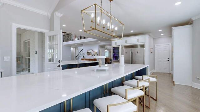 kitchen featuring stainless steel built in fridge, decorative light fixtures, a kitchen island, baseboards, and crown molding