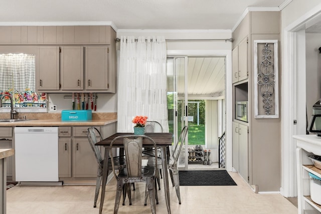 kitchen featuring light countertops, dishwasher, crown molding, and a sink