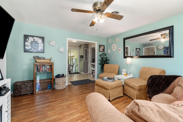 living area featuring visible vents, wood finished floors, and a ceiling fan