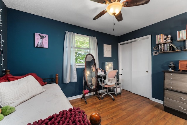 bedroom featuring a closet, ceiling fan, wood finished floors, and baseboards