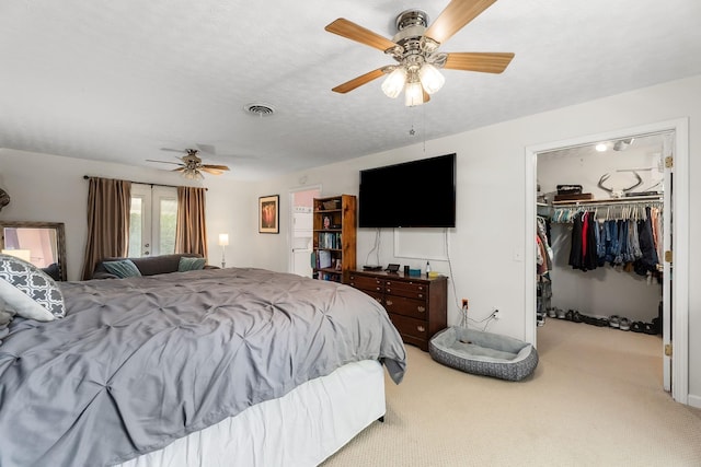 bedroom featuring a closet, carpet flooring, a walk in closet, visible vents, and a ceiling fan