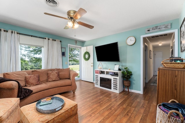 living area with visible vents, ceiling fan, wood finished floors, and baseboards