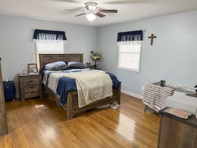 bedroom with baseboards, light wood-type flooring, and multiple windows