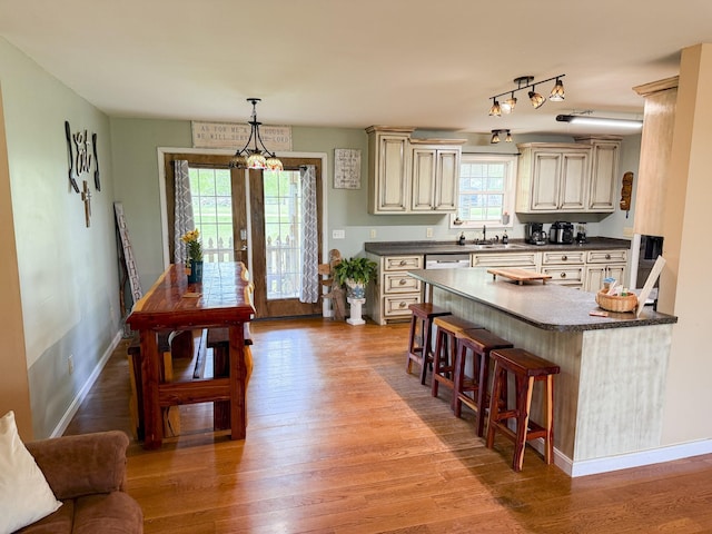 kitchen featuring cream cabinetry, dark countertops, a breakfast bar area, and light wood-type flooring