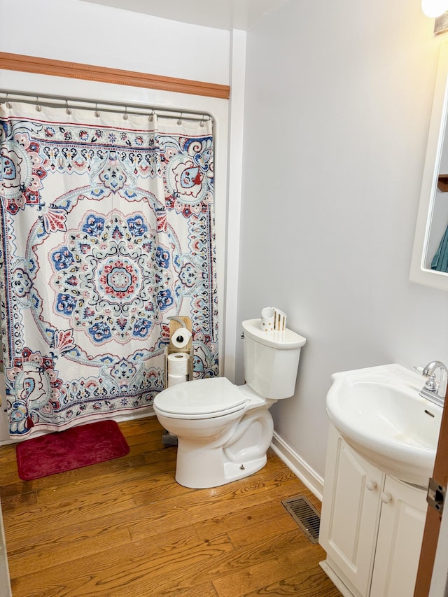 bathroom featuring visible vents, baseboards, toilet, wood finished floors, and vanity