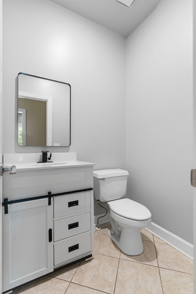 half bath featuring vanity, baseboards, tile patterned floors, and toilet