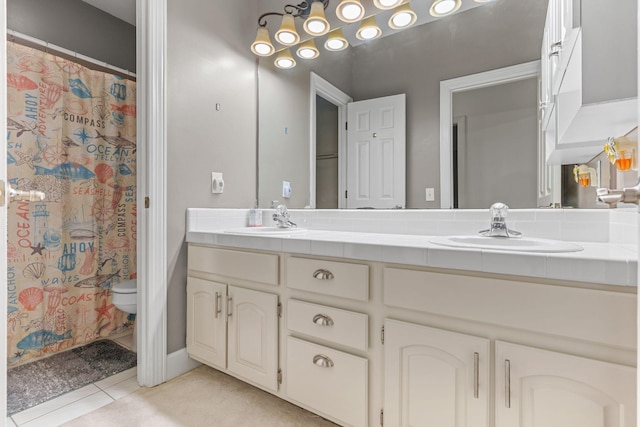 full bathroom featuring double vanity, toilet, a sink, and tile patterned flooring