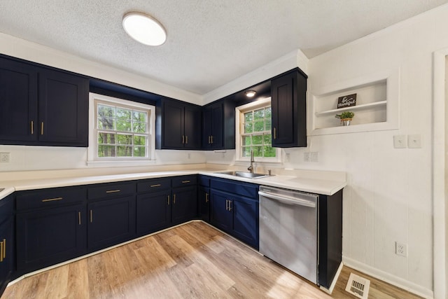 kitchen featuring a sink, light wood finished floors, dishwasher, a textured ceiling, and ornamental molding