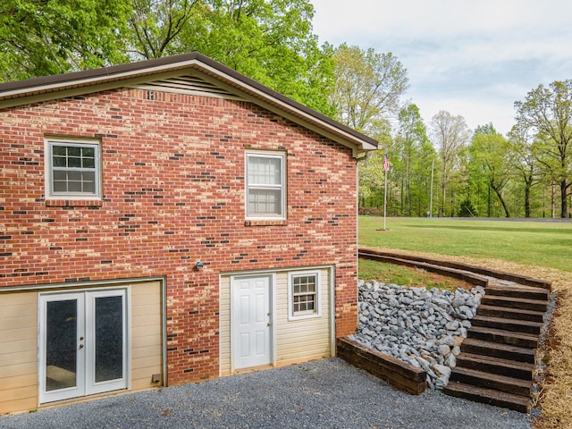 back of property with a yard, brick siding, and french doors