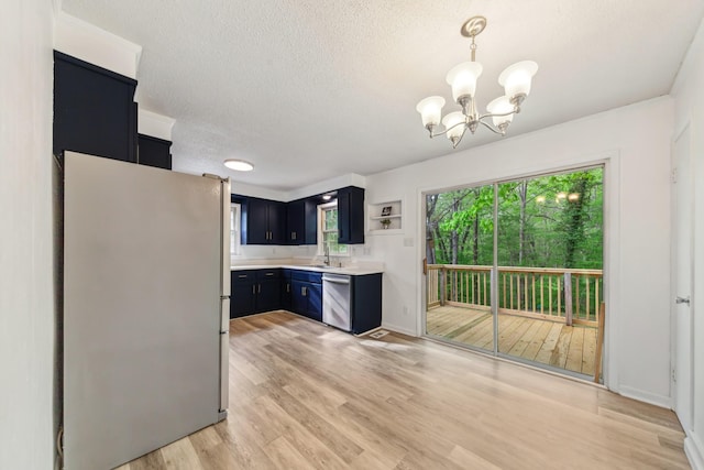 kitchen featuring light countertops, a textured ceiling, a chandelier, a sink, and appliances with stainless steel finishes