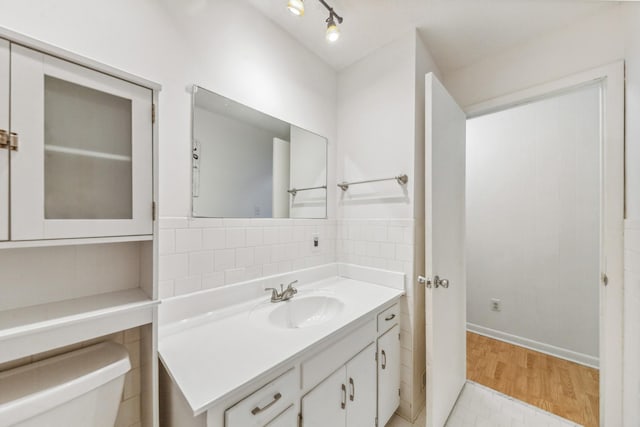 half bathroom featuring toilet, baseboards, wood finished floors, and vanity