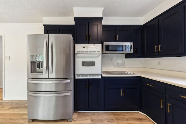 kitchen featuring crown molding, light countertops, a textured ceiling, light wood finished floors, and appliances with stainless steel finishes