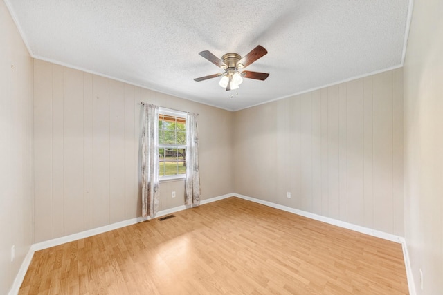 spare room featuring visible vents, a textured ceiling, light wood-style flooring, and ceiling fan