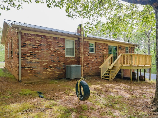 back of property featuring central air condition unit, a wooden deck, metal roof, and brick siding