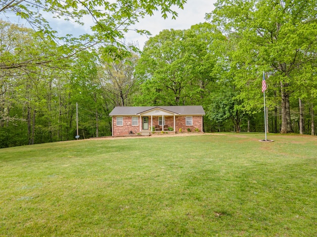 view of front of home with brick siding, a front lawn, covered porch, and metal roof