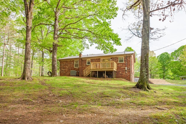 rear view of property with a chimney, a lawn, a deck, stairway, and brick siding