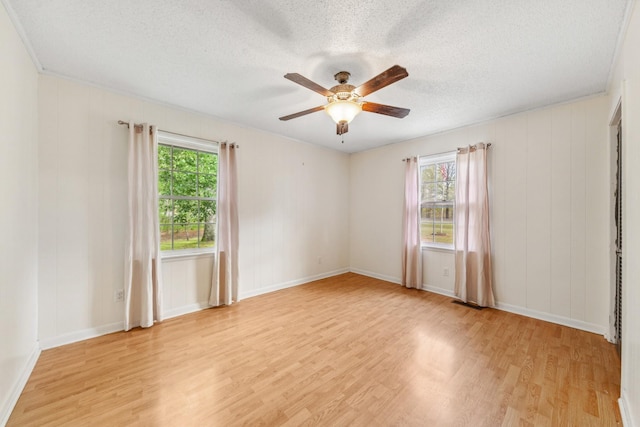 empty room with a ceiling fan, light wood finished floors, a textured ceiling, and a wealth of natural light