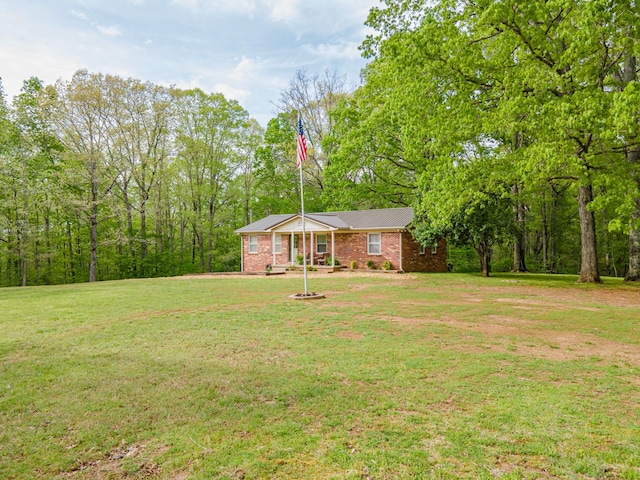 view of front of property with brick siding, a front yard, and metal roof