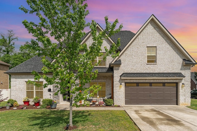 view of front of house featuring a lawn, a shingled roof, and driveway