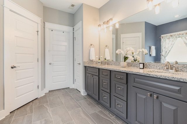 bathroom with double vanity, visible vents, and a sink