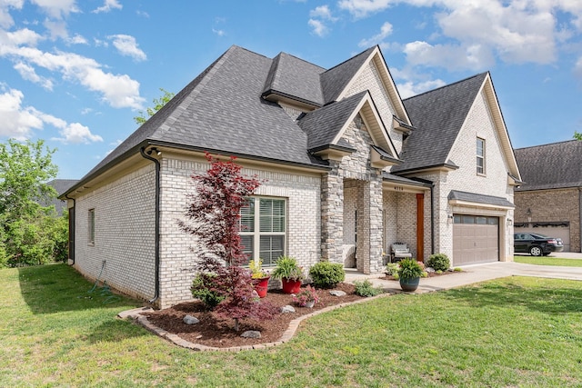 french country inspired facade with brick siding, a shingled roof, a front yard, and concrete driveway