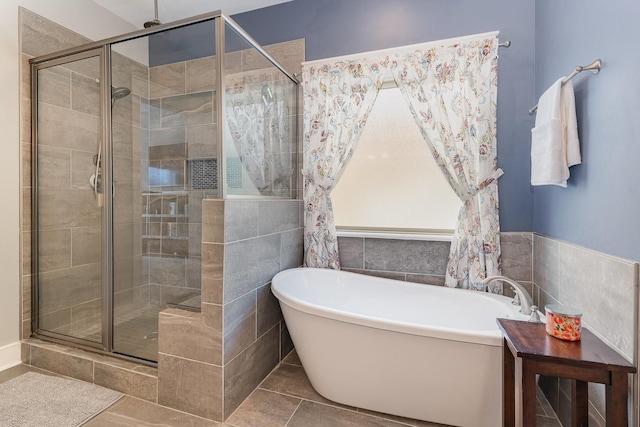 bathroom with tile patterned floors, a soaking tub, tile walls, and a shower stall
