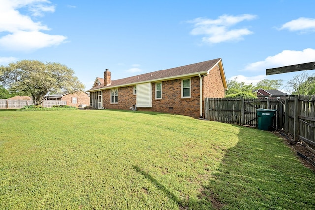 rear view of property featuring brick siding, a fenced backyard, and a lawn