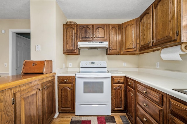 kitchen with white electric range oven, light wood-type flooring, light countertops, a textured ceiling, and under cabinet range hood