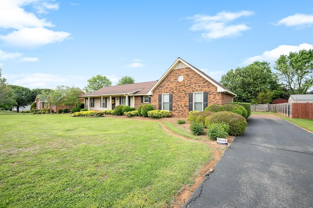 ranch-style home featuring fence, a front lawn, and brick siding