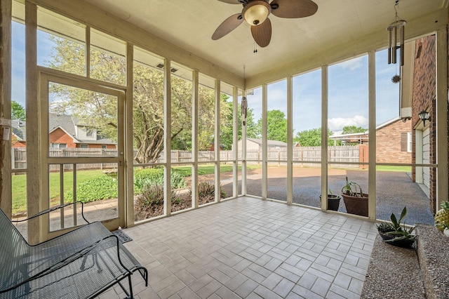 unfurnished sunroom with a ceiling fan and a wealth of natural light