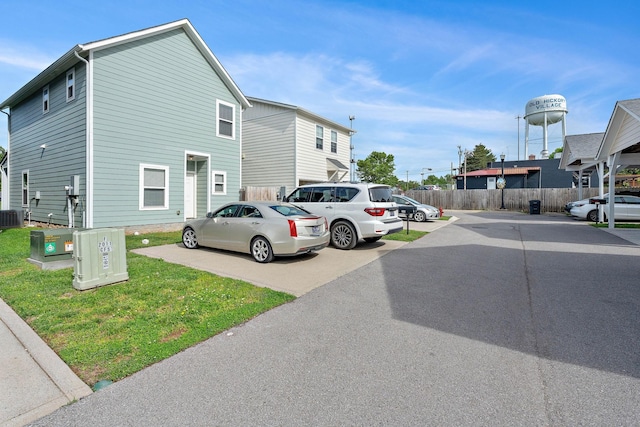 view of home's exterior with uncovered parking, fence, and central AC unit