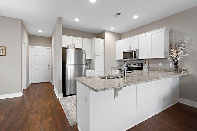 kitchen featuring visible vents, a peninsula, baseboards, a sink, and stainless steel appliances