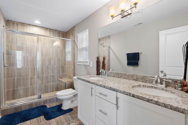bathroom with a sink, a shower stall, toilet, and visible vents