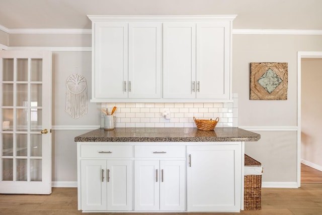bar with baseboards, ornamental molding, backsplash, and light wood finished floors