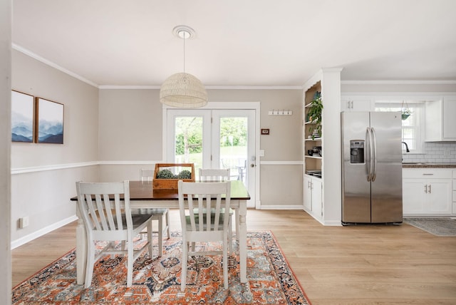 dining area with baseboards, ornamental molding, and light wood-type flooring