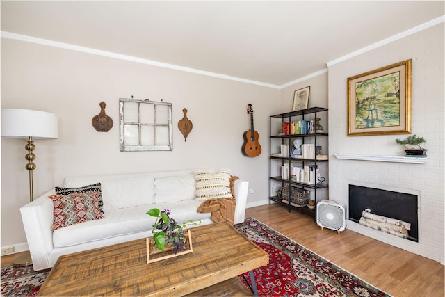 living room with baseboards, ornamental molding, a brick fireplace, and wood finished floors