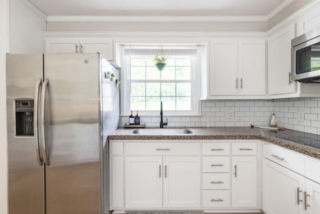 kitchen with a sink, white cabinets, ornamental molding, and stainless steel appliances