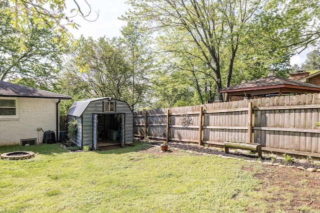 view of yard featuring a fenced backyard, an outdoor fire pit, a storage shed, and an outbuilding