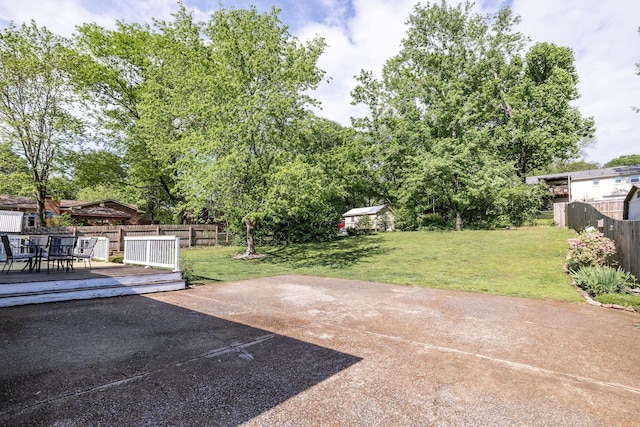 view of yard featuring a patio, fence, a wooden deck, and outdoor dining area